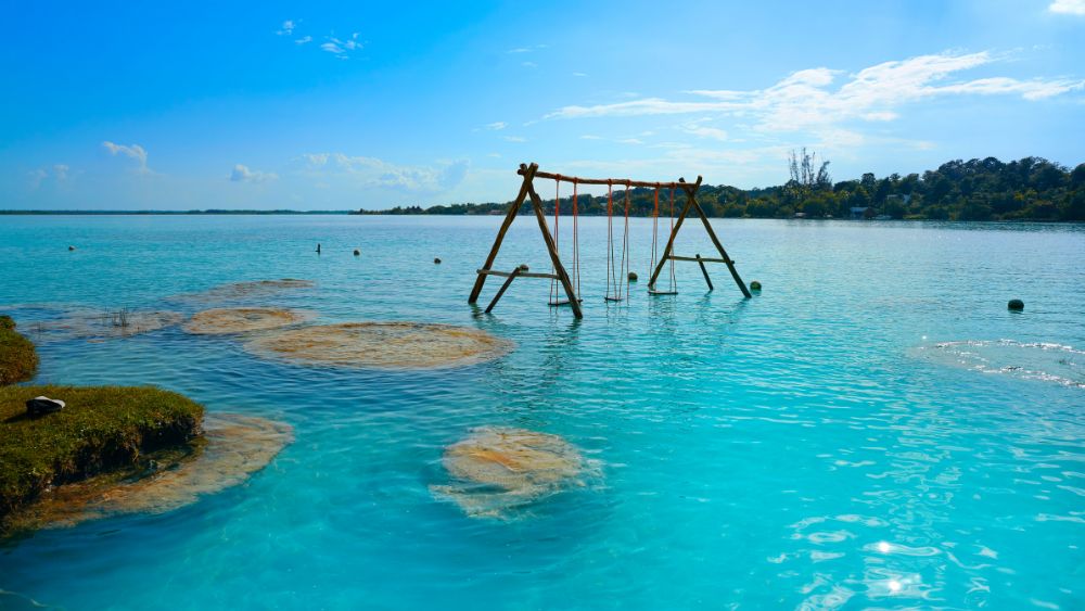 wooden swing in the middle of a blue body of water- Amazing Things to Do in Mexico's Yucatan Peninsula