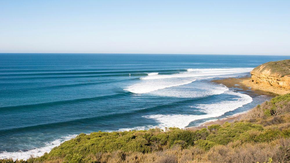 image of a wavy beach with lushy green hill nearby - Best Beaches in Australia