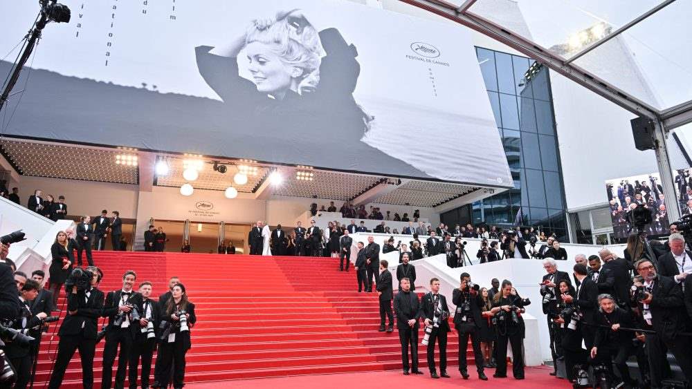 photographer line up outside the building with red carpet in the middle