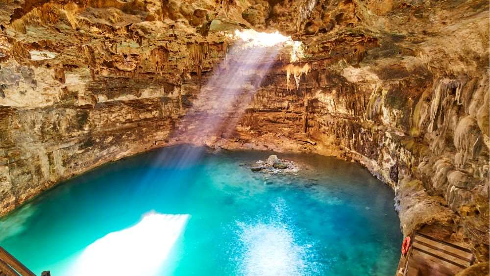 body of water inside the cave with small hole showing light from outside- Amazing Things to Do in Mexico's Yucatan Peninsula