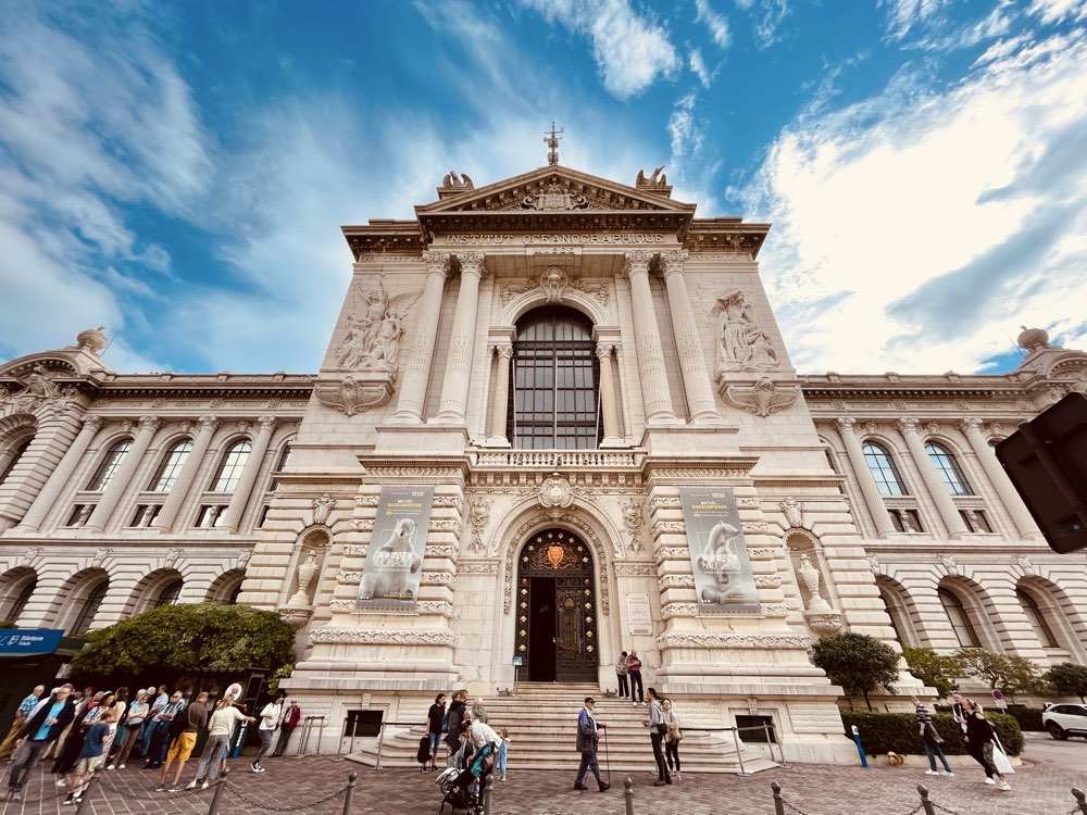 people walking and standing in front of a white old building