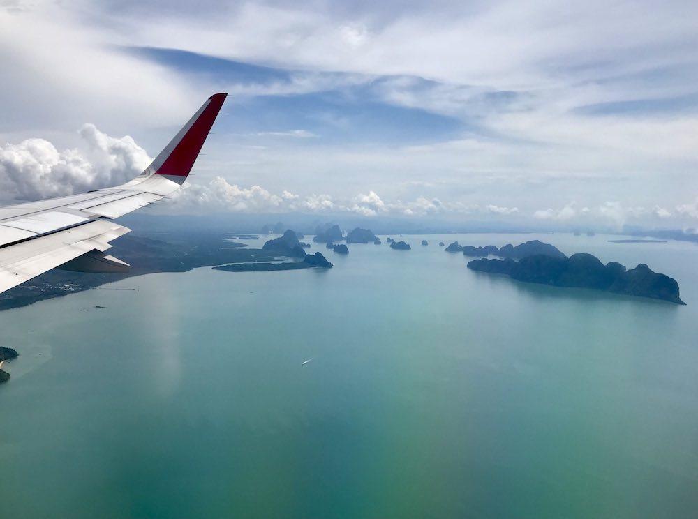 view shows wing of an airplane and island in the ocean