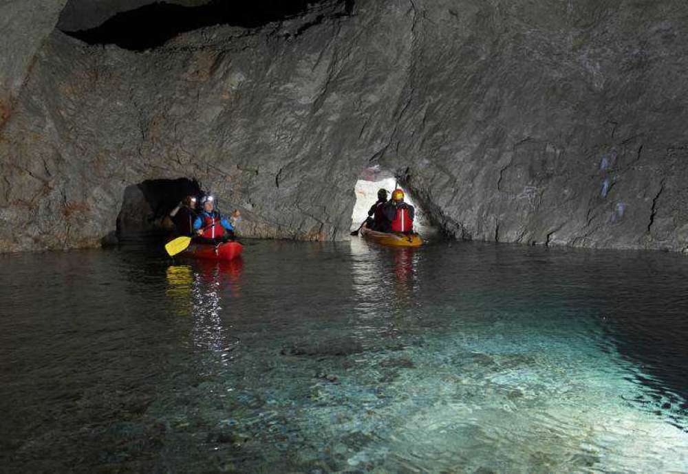 people rowing kayak boat inside the cave