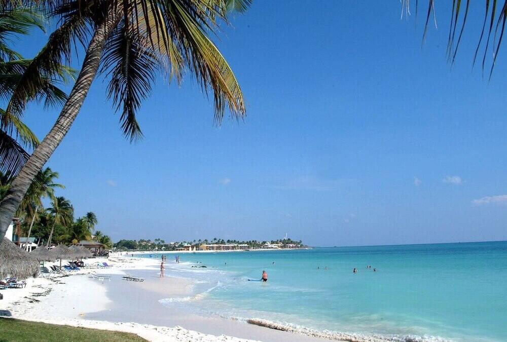 clam blue beach and white sand with people around the Palm Beach, Aruba