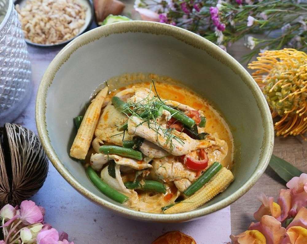 orange soup top with green leaves and other veggies and chicken best thai food in thailand
