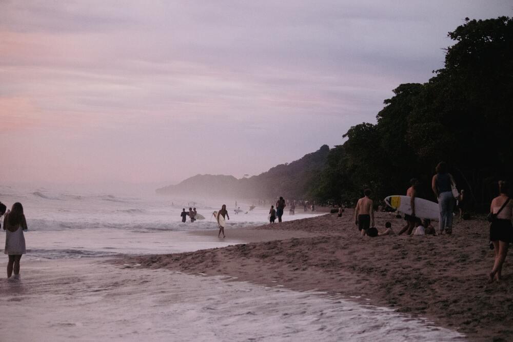 bunch of people and some are holding a surf board in a wavy ocean