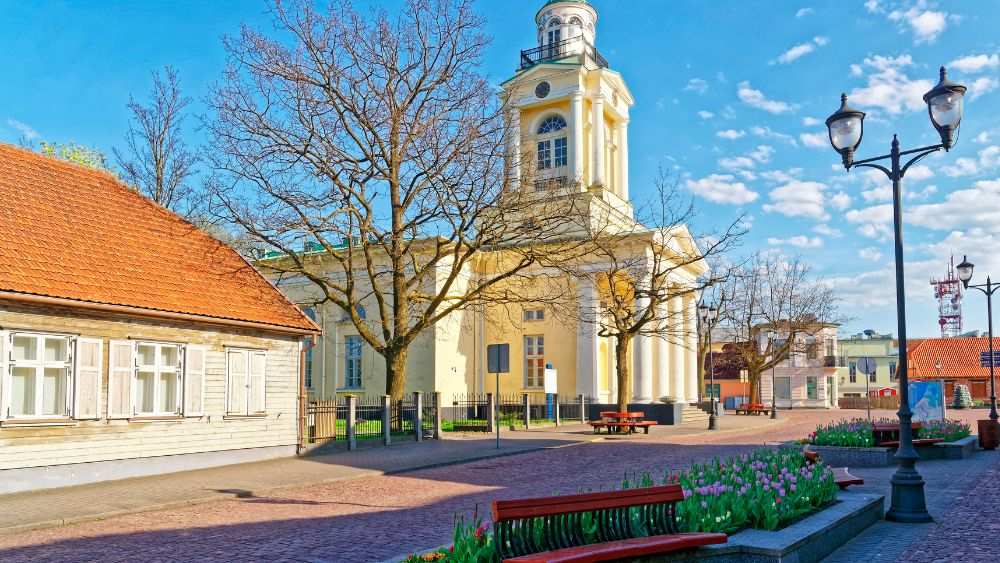 concrete building in the park with wooden bench near flowers- latvia digital nomad visa